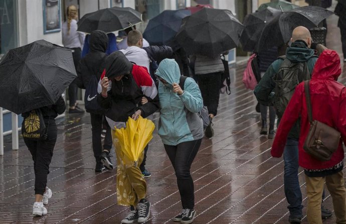 Personas caminando por la calle bajo la lluvia
