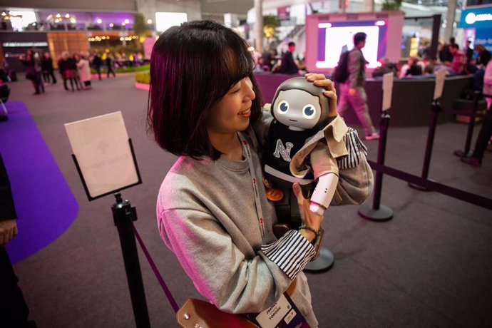 Un mujer lleva en brazos a un robot durante el Mobile World Congress Barcelona - MWC 2019.