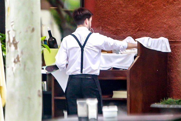 Un camarero atiende a los clientes de una terraza en una sidrería de Madrid.