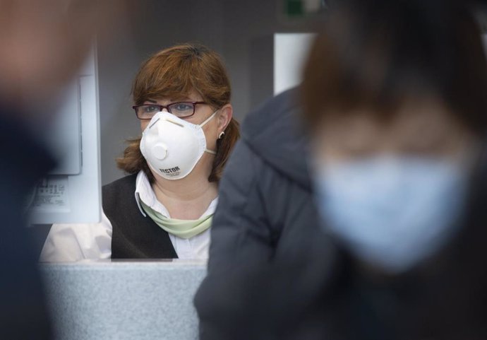 30 January 2020, Frankfurt/Main: A China Southern Airlines employee wears a face masks as passengers wait at Frankfurt Airport for the check-in of the Chinese airline Air China. Photo: Dorothee Barth/dpa