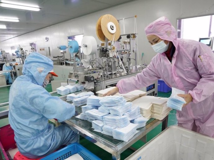 Los trabajadores hacen máscaras faciales en el taller de una empresa en Wuhan, provincia de Hubei, en el centro de China, el 28 de enero de 2020.