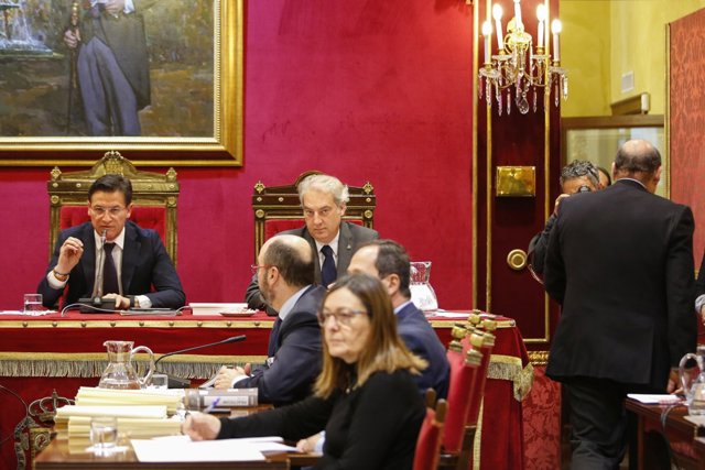 El presidente del PP de Granada, Sebastián Pérez (a la derecha), abandona el Pleno del Ayuntamiento tras su dimisión al frente del partido mientras interviene el alcalde, Luis Salvador (Ciudadanos)