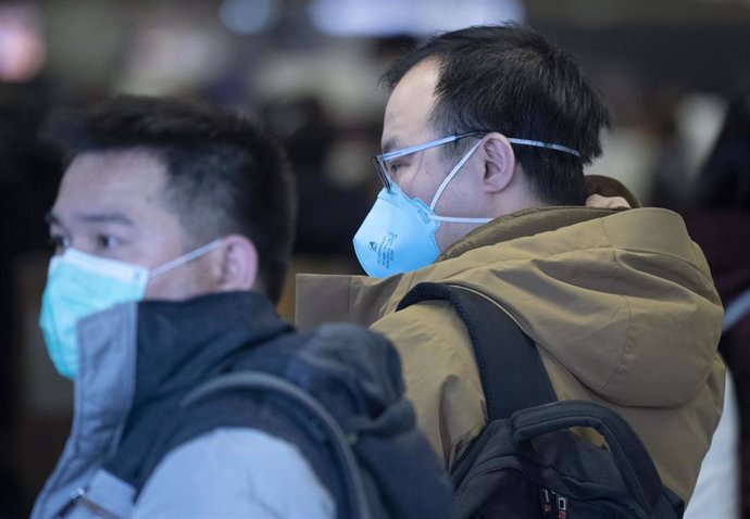 30 January 2020, Frankfurt/Main: Passengers wear face masks as they wait at Frankfurt Airport for the check-in of the Chinese airline Air China. Photo: Boris Roessler/dpa