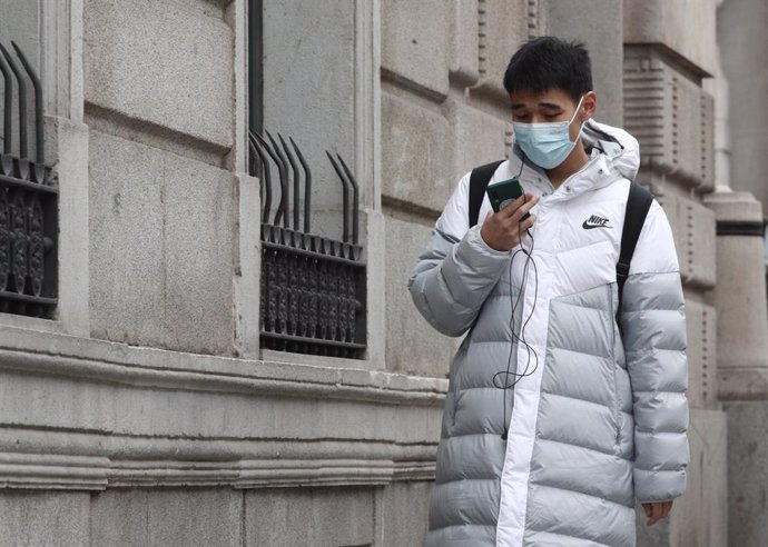 Un asiático pasea por la calle con una mascarilla.
