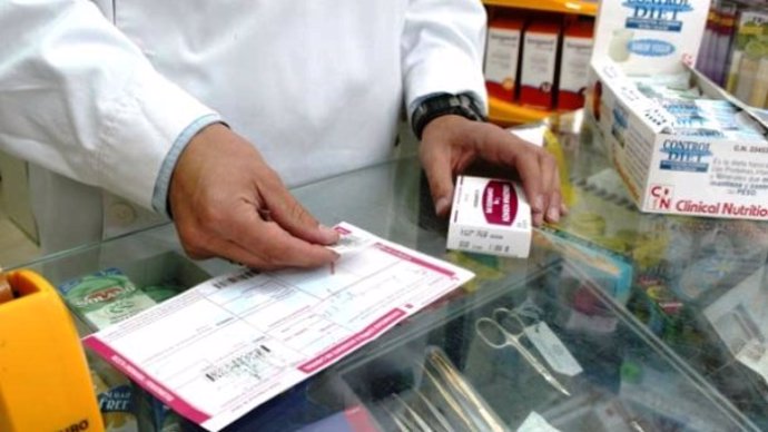 Un farmacéutico consulta la receta de un paciente en una farmacia