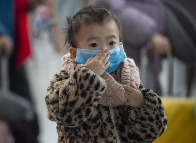 30 January 2020, Frankfurt/Main: A child wears a face mask as he waits with his mother at Frankfurt Airport for the check-in of the Chinese airline Air China. Photo: Boris Roessler/dpa