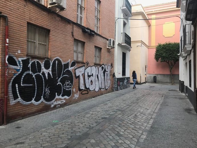 Una mujer pasea por una calle con pintadas en Sevilla