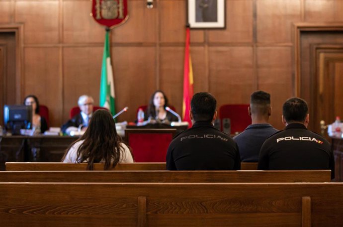 Los acusados de maltratar y asesinar  a su bebé de seis meses sentados en el banquillo de los acusados custodiados por la Policía Nacional al inicio del juicio 