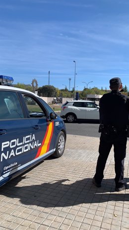 Agente de Policía Nacional con coche patrulla en la calle