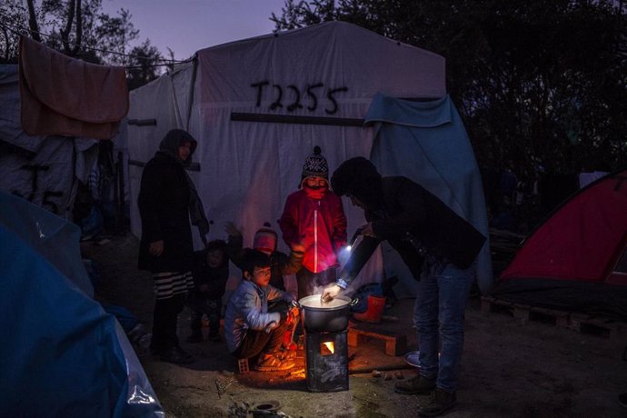 Una familia de migrantes hace fuego junto al campo de refugiados de Moria, en Lesbos