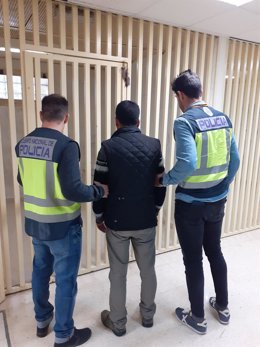 Imagen de uno de los detenidos, custodiado por la Policía Nacional