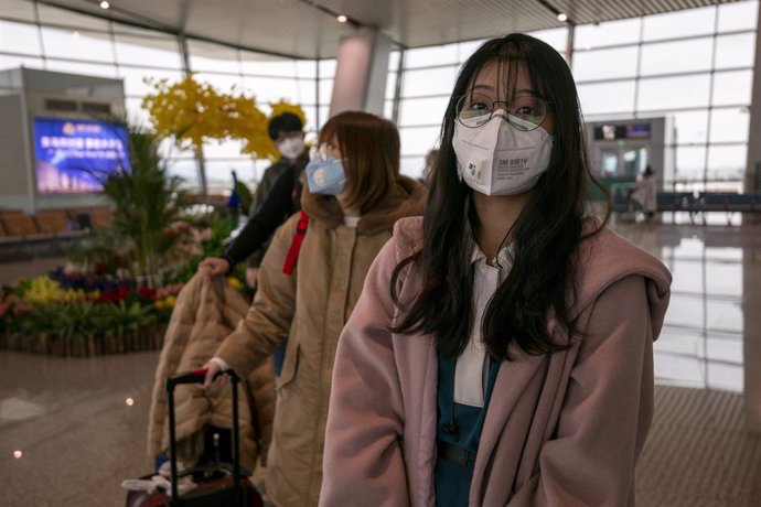 Una mujer de viaje con una mascarilla para protegerse del brote del nuevo coronavirus. 