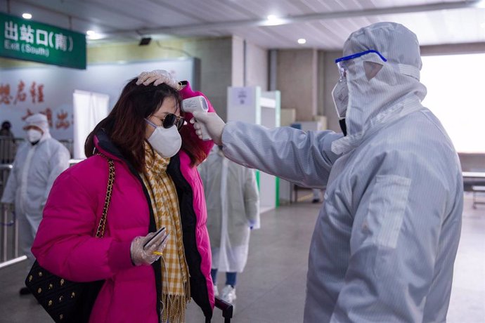 10 February 2020, China, Jiangsu: A doctor uses a forehead digital thermometer to measure the body temperature of a woman at the Nanjing railway station, as a precautionary measure to prevent the spread of coronavirus. 