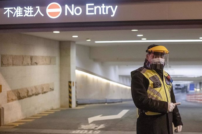 February 10, 2020, Shanghai China - A security guard in a surgical mask and a clear plastic visor holds an electronic thermometer and stands outside car park at the Kerry Center luxiury mall on West Nanjing Road, usually one of Shanghai's busiest street