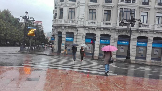 Personas con paraguas para protegerse de la lluvia en una calle de Oviedo. 