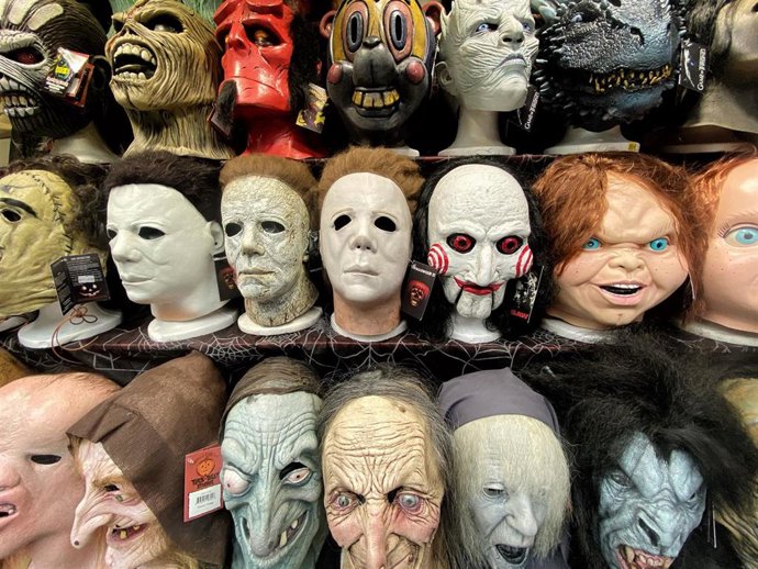 Caretas de personajes de miedo y villanos de películas en una tienda de disfraces de Madrid a un día de la noche de Halloween.