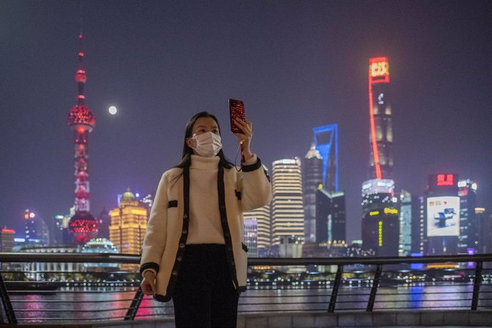 Una mujer con máscara se saca una foto en Shangái. 