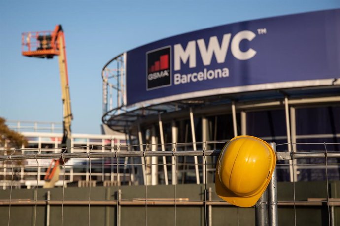 Un casco de obra amarillo colgado en una de las vallas que cierran el recinto del Mobile World Congress (MWC) durante el desmantelamiento de los stands tras la cancelación de la feria.