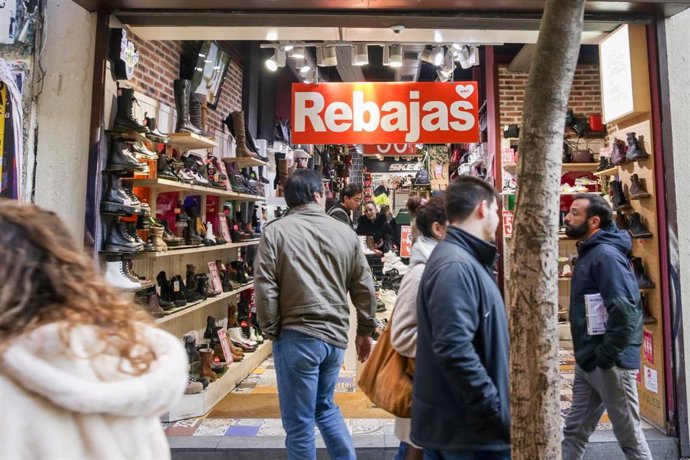 Varias personas pasean junto a una tienda de zapatos de Madrid, donde ya ha empezado la temporada de rebajas.