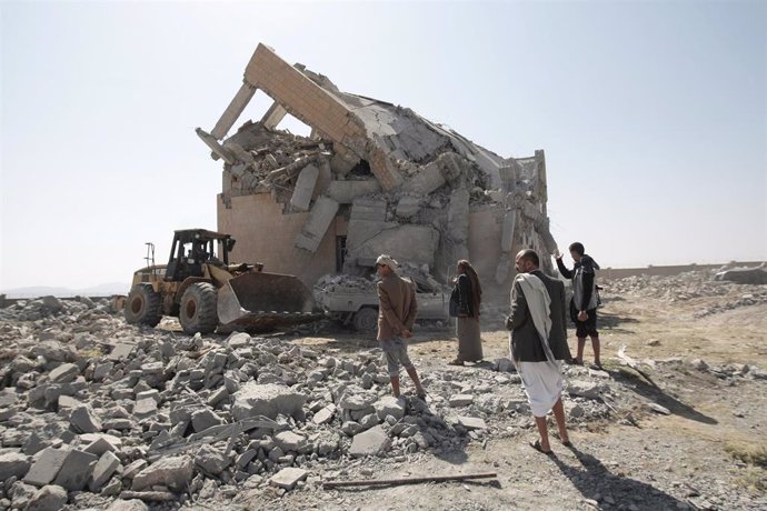 Personas junto a un edificio destruido en un bombardeo aéreo en Yemen