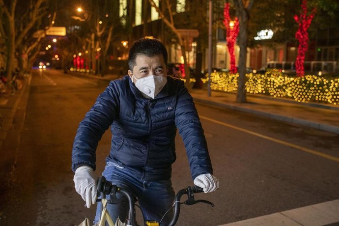 Un hombre con mascarilla en una bicicleta en Shanghái. 
