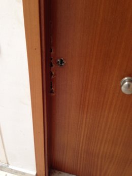 Estado de la puerta de una de las viviendas ocupadas en la provincia de Huelva tras ser forzada