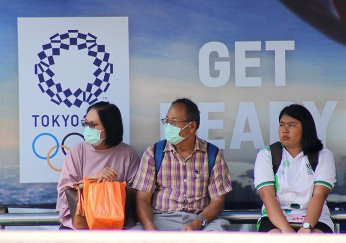 Ciudadanos tailandeses ante un cartel de los Juegos Olímpicos de Tokio en Bangkok
