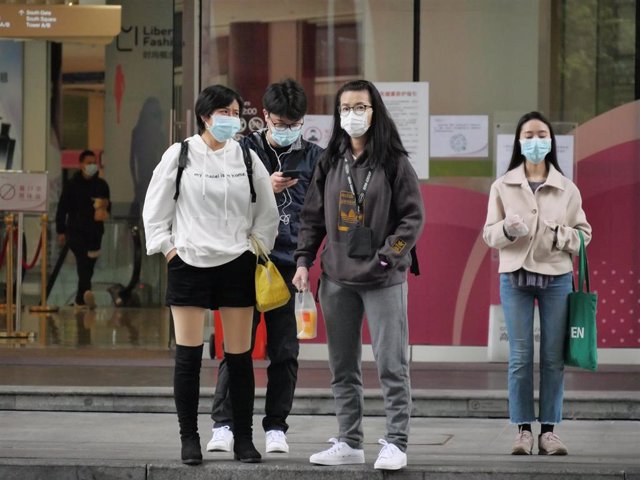 Pasajeros esperan con mascarillas en una estación de tren de China. 