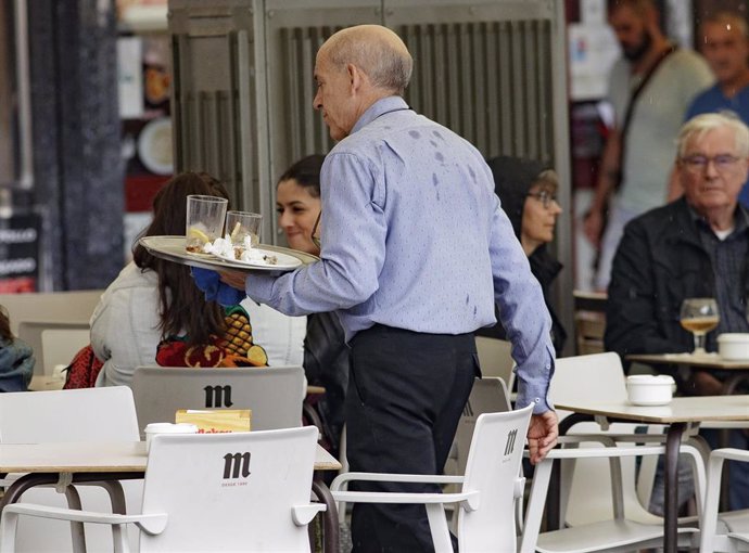Un camarero porta una bandeja en una terraza de un bar de Madrid.