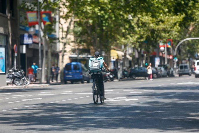 Un 'rider' de la compañía de comida a domicilio, Deliveroo, circula con su bicicleta por una calle de Madrid.