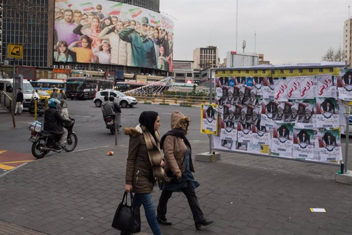Dos mujeres pasan por delante de carteles electorales en Teherán