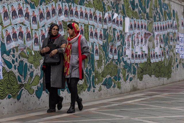 Dos mujeres pasan junto a carteles electorales antes de las parlamentarias en Irán