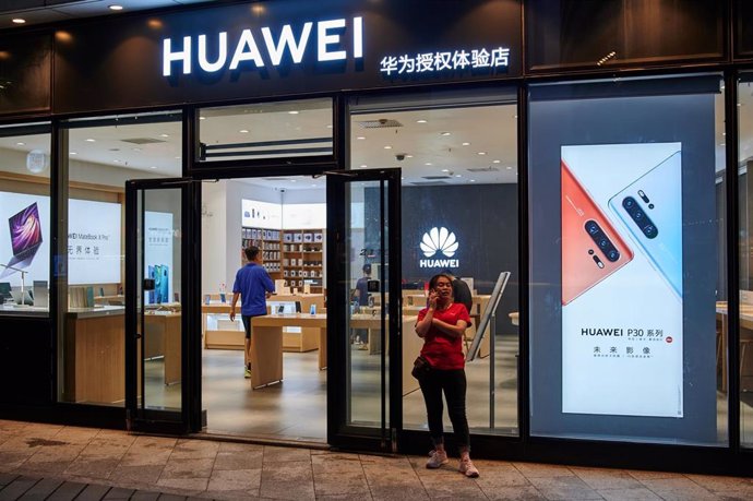 August 10, 2019 - Beijing, China: A woman talks on a mobile phone outside a Huawei store. Despite Huawei's recent announcement of in-house developed operating system HarmonyOS which is designed more for IOT devices rather than cell phones, Huawei is yea