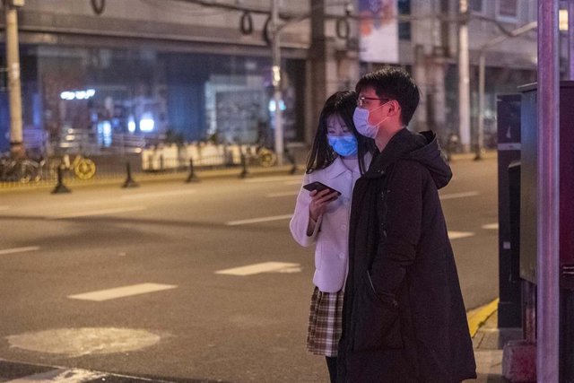 Una pareja que viste mascarillas para evitar el contagio del nuevo coronavirus camina por la otrora ajetreada Shanghai.