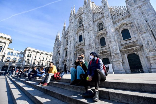 24 February 2020, Italy, Milan: Tourists take sit while wearing surgical masks on the steps of the Duomo di Milano amid the outbreak of the coronavirus. Photo: Claudio Furlan/LaPresse via ZUMA Press/dpa