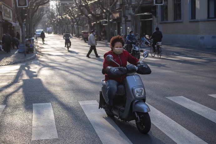February 24, 2020 - Shanghai, China: A woman on a scooter wears protective mask as she crosses an intersection on Hefei Road. According to official figures more than 77,000 people have been infected with the virus and 2,600 people have died from the dis