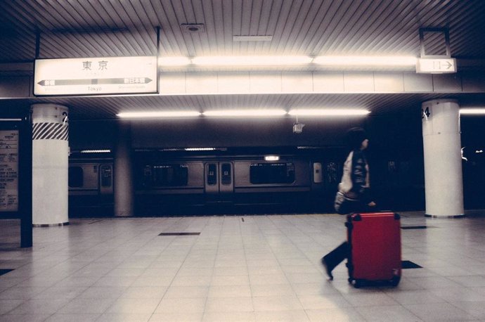 Foto recurso mujer con una maleta en una estación de tren