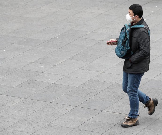 Un hombre asiático pasea con una mascarilla protectora, mientaras las farmacias registran una alta demanda de estas, por parte de ciudadanos chinos tras el coronavirus, en Madrid (España), a 30 de enero/Archivo