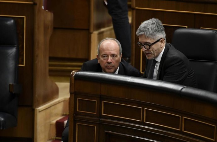 El ministro de Interior, Fernando Grande-Marlaska (dch) mantiene una conversación con el ministro de Justicia, Juan Carlos Campo, (izq) durante una sesión plenaria en el Congreso de los Diputados 