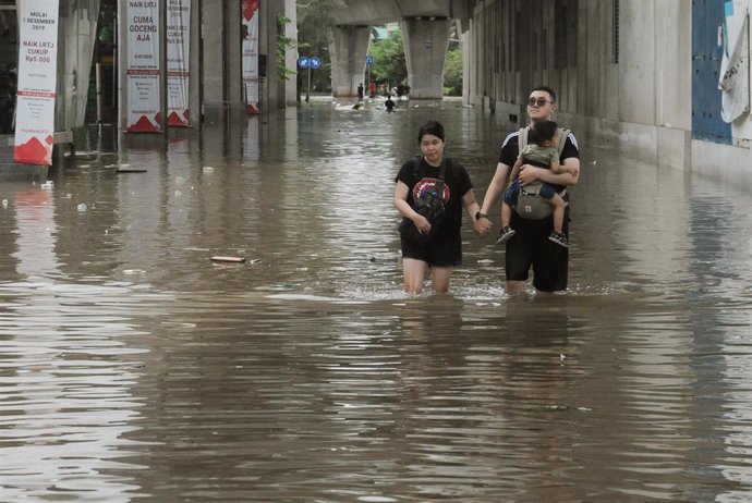 Una pareja camina pro una calle inundada en Indonesia. 