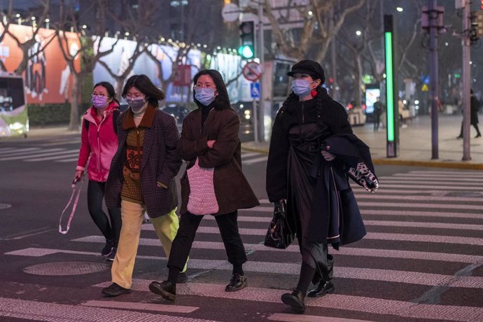 February 25, 2020 - Shanghai China: Pedestrians wear surgical masks as protection against the coronavirus as they cross Ruijin and Huaihai Roads in the former French Concession.
