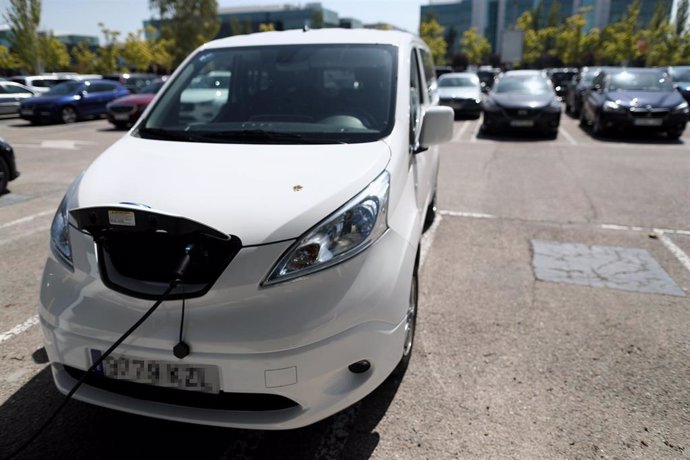 Un coche híbrido se carga en un punto de recarga de batería.