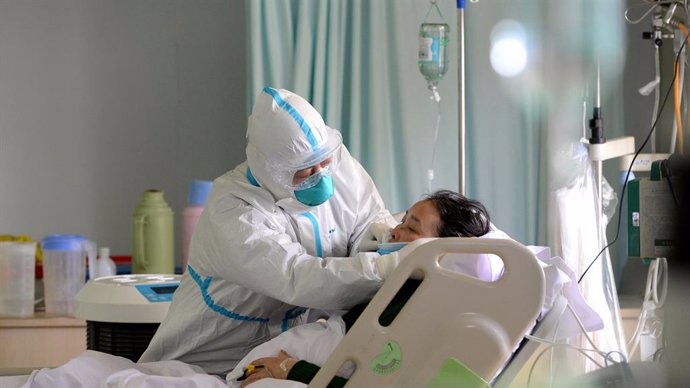 Un metge militar atén a un pacient malalt de coronavirus en l'unitat de vigilncia intensiva, en Xinesa.