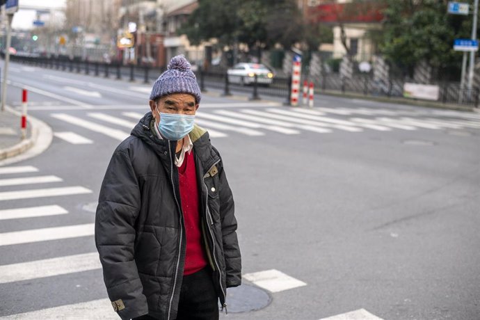 February 25, 2020 - Shanghai China: An elderly man wears a surgical mask as protection against the coronavirus as he crosses a street in Hungpu District According to official figures more than 80,000 people have been infected with the virus and at least
