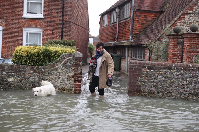 Un hombre sale de su casa ante las fuertes inundaciones provocadas por los temporales en Reino Unido. 