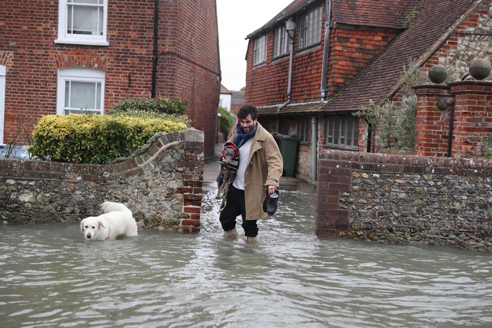 Un hombre sale de su casa ante las fuertes inundaciones provocadas por los temporales en Reino Unido.