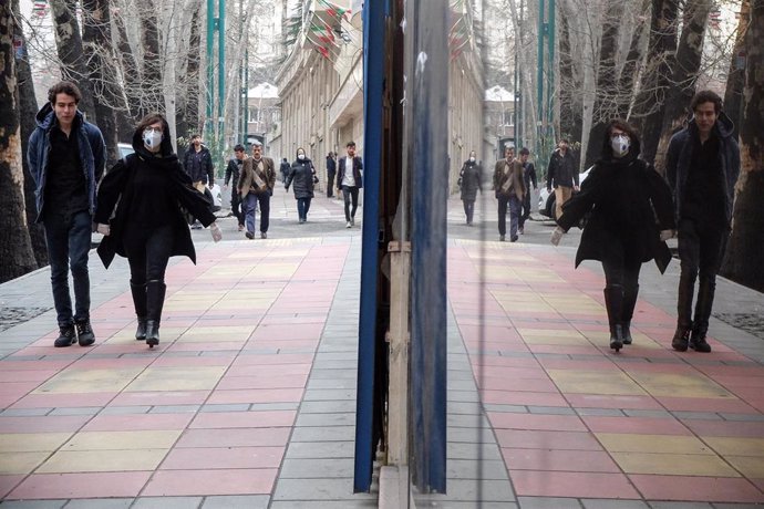 Iraníes con máscaras en una calle de Teherán, afectada por el brote de nuevo coronavirus