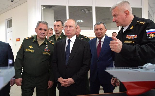 Vladimir Putin acompañado por el ministro de Defensa ruso, el general Sergei Shoigu, con uniforme verde, acompañado de otros altos mandos militares