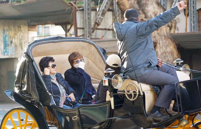 Turista oriental con mascarilla paseando en coche de caballo por las calles de Sevilla,a cinco de febrero del 2020