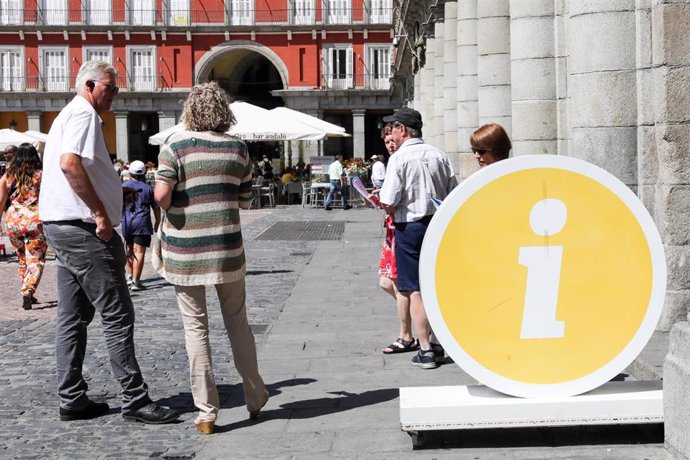 Varios turistas cerda de la oficina de turismo de la Comunidad de Madrid ubicada en la Plaza Mayor de Madrid.